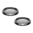 Two black, circular mesh speaker covers with raised, concentric grills are displayed side by side against a plain white background. Each cover features a small, rectangular white label at the base.