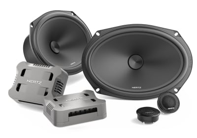 Car audio speakers and components arranged on a white background; two large oval speakers, two smaller round tweeters, and two rectangular crossovers labeled "HERTZ".