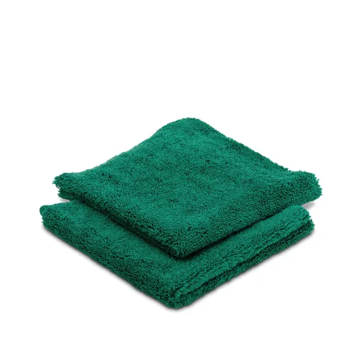 Two green towels are stacked neatly on top of each other against a plain white background.