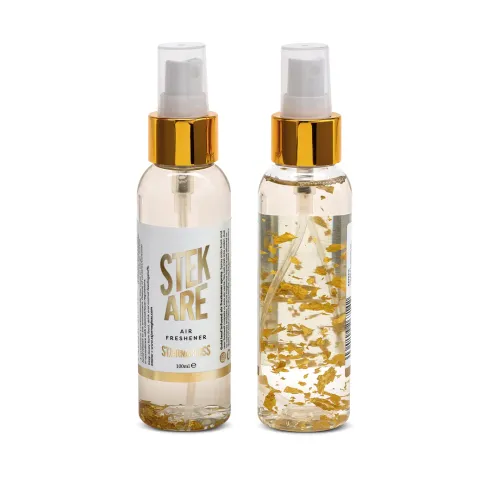 Two transparent air freshener spray bottles with gold caps, containing liquid with gold flakes inside. The label reads: "STEK ARE AIR FRESHENER STJARNAGLOSS 100ML."