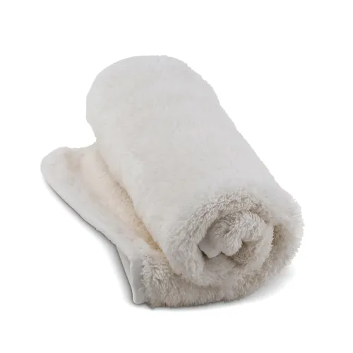 A rolled-up, fluffy, white towel placed on a white surface.