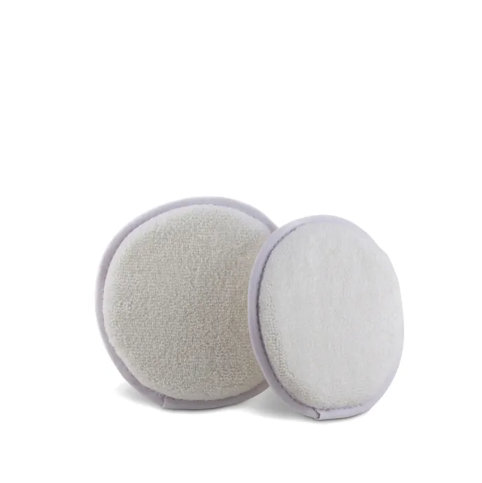Two round, white, textured makeup-removal pads are placed side by side on a plain white background, with one slightly overlapping the other.
