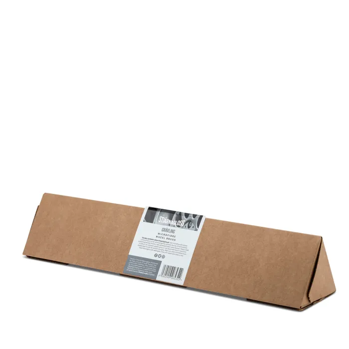 A long, triangular, brown cardboard box sits on a white surface, featuring a central label with text: "Stjärnagloss GRIMIG WHEELBRUSH BRAKE DUST WHEEL BRUSH".