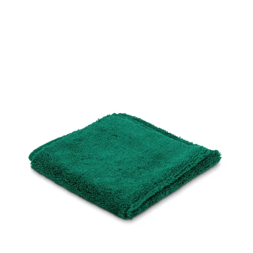 A folded green towel sits on a white surface.
