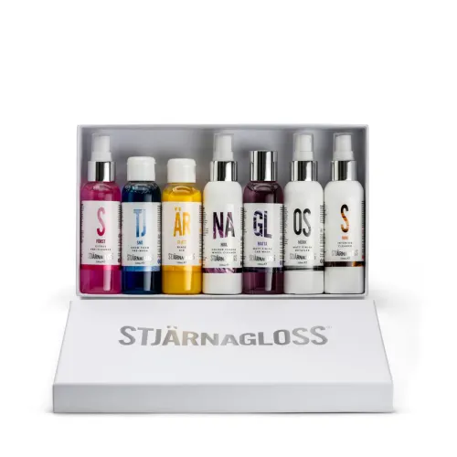 Bottles arranged in a white box with a lid labeled "STJÄRNAGLOSS"; bottles feature text including "FÖRST," "SNÖ," "ÄR," "NÄR," "GL," "OS," "S," and varied colors, possibly for car care.