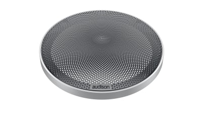 A circular speaker grille with a perforated, geometric design; the brand name "audison" is printed on the front edge. The grille is placed against a plain white background.