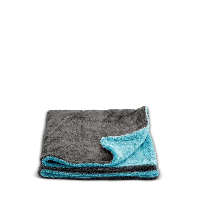 A folded microfiber towel, gray on top and blue on the underside, rests on a white surface, showing its dual-colored design.