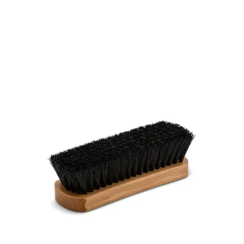 A wooden-handled brush with stiff black bristles sits on a plain white background.