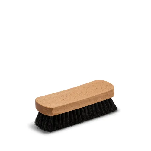 A rectangular wooden brush with black bristles lying horizontally on a white background.