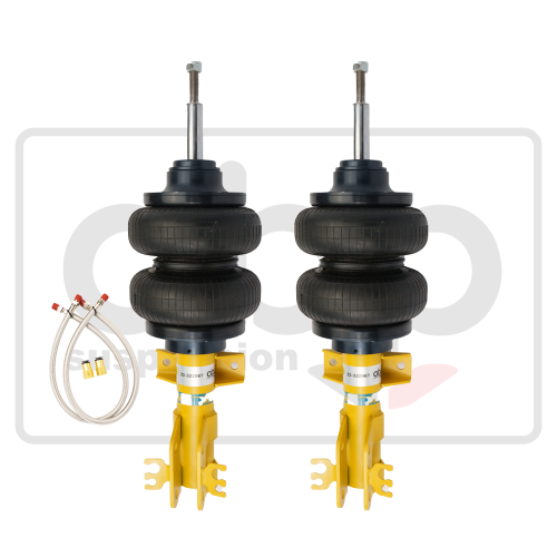 Two black rubber air springs with attached yellow brackets stand upright. Flexible metallic hoses with red caps and yellow connectors lie nearby. Background features faint text "aero."