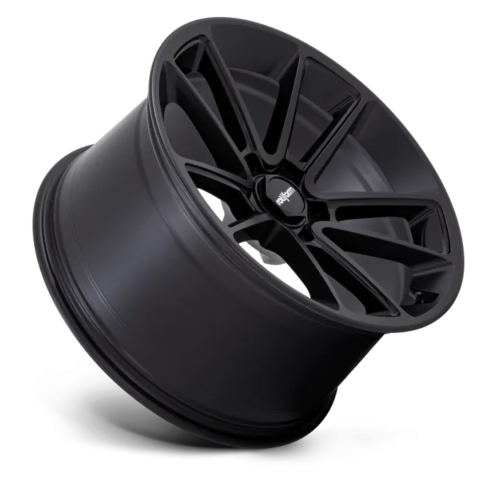 A matte black wheel rim with a multi-spoke design displaying "rhythm" on the center cap, angled against a dark background.