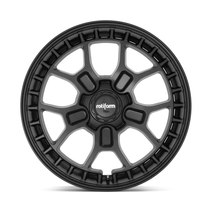 A black alloy wheel with the brand name "rotiform" in the center, featuring a unique geometric design of seven double spokes against a plain, light-colored background.