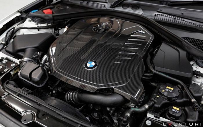 A BMW engine with a carbon fiber cover featuring the BMW logo is displayed within the engine compartment of a car. The word "EVENTURI" is visible in the bottom right corner.