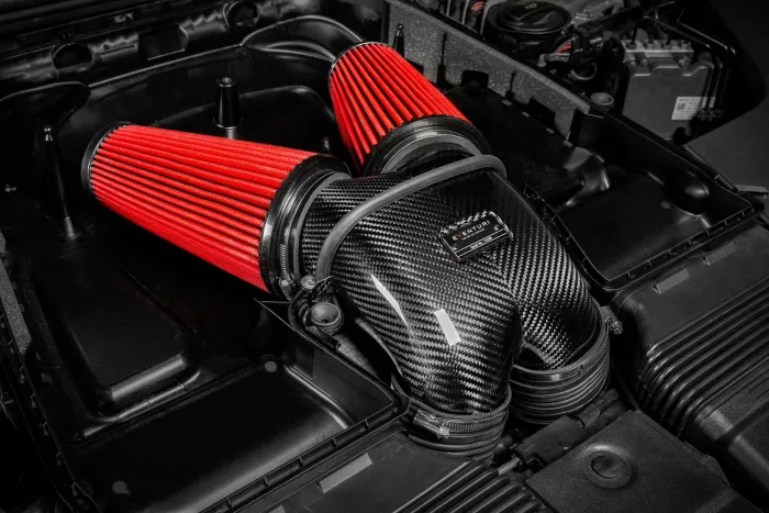 Two large red air filters connect to a carbon-fiber intake manifold labeled "Eventuri, Super V8," inside a car engine compartment. Surrounding components appear clean and well-organized.