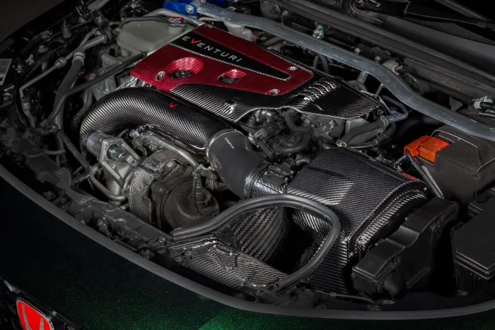 Automotive engine featuring a red and black carbon fiber cover labeled "Eventuri," surrounded by various mechanical components and hoses inside a vehicle's engine bay.