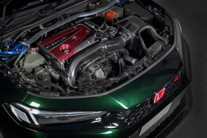Car engine bay with a prominent "EVENTURI" intake system, parts in carbon fiber and red accents, situated within a clean, glossy dark green Honda vehicle.