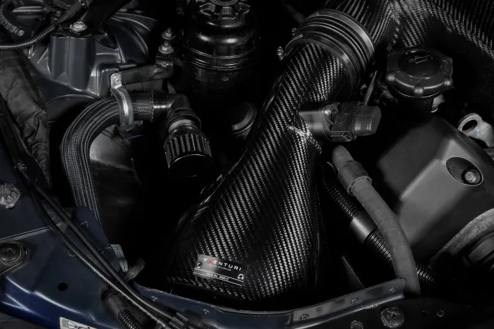 A carbon fiber air intake system (Eventuri, Serial No. 5B8C0) is installed in a car engine bay, flanked by various wires, hoses, and a coolant reservoir.