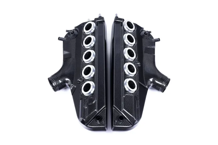 Carbon fiber intake manifold with eight circular ports on each side, symmetrically placed, positioned on a white background.