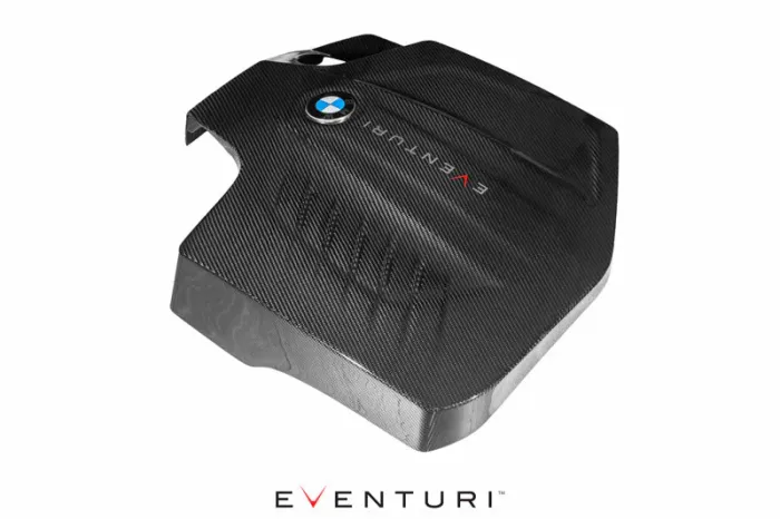 A carbon-fiber engine cover with a BMW logo and "EVENTURI" text, resting on a white background. The brand name "EVENTURI" appears prominently below the object.