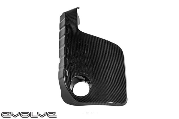 Black carbon fiber automotive component with a circular cutout, angled edges, and textured surface, placed against a white background. The word "evolve" is in the bottom left corner.