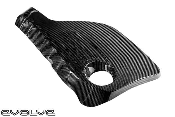 A black carbon fiber automotive part with a circular cutout sits on a white background. "Evolve" text is positioned at the bottom left corner.