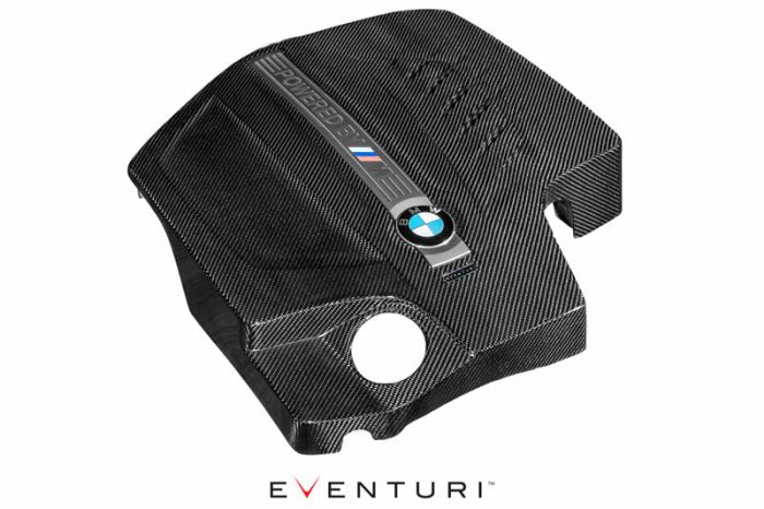 Carbon fiber engine cover for a BMW, featuring a label with "POWERED BY M" and the BMW logo. It is displayed on a white background with "EVENTURI" text below.