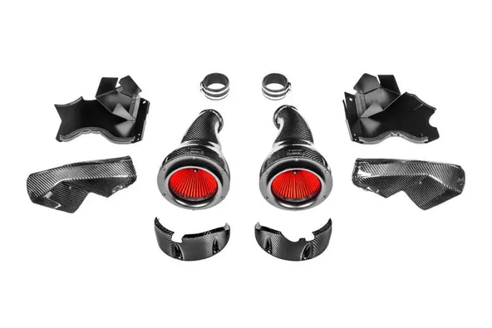 Carbon fiber automotive air intake system with red filters laid out, including ducts, clamps, and housing components, all arranged against a plain white background.