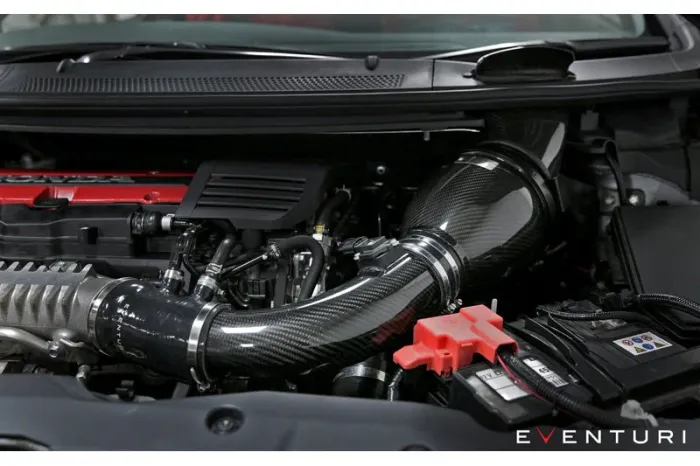 A carbon fiber air intake system is installed in the engine bay of a car, surrounded by various engine components and cables. Text: EVENTURI.