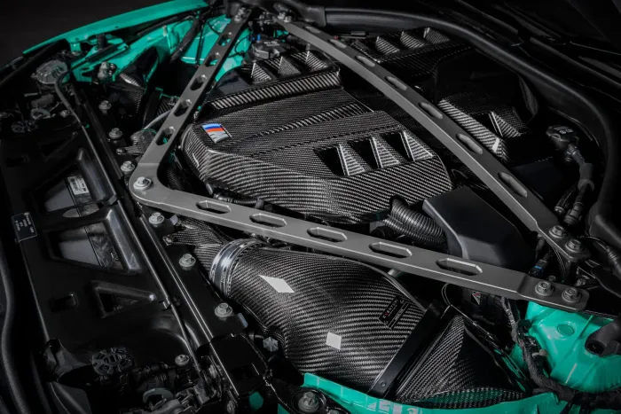 A car engine with carbon fiber parts and reinforced strut braces in a clean, well-lit engine bay showcasing performance-oriented modifications.