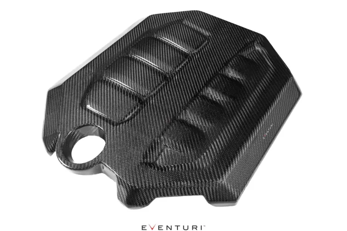 Carbon fiber engine cover with a sleek design featuring ridged patterns, positioned diagonally against a white background. Text at the bottom reads "EVENTURI".