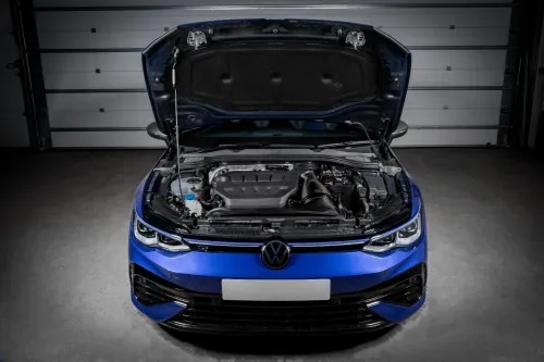 A blue car with its hood open, revealing the engine, parked inside a garage with closed, grey metal doors in the background.