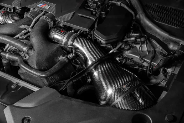 A sleek carbon fiber air intake with a "Venturi" logo is installed in a high-performance engine bay, surrounded by various cables, hoses, and engine components.