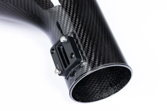 A carbon fiber tube with a black metal mounting bracket, featuring four screws, is positioned against a plain white background. The bracket is labeled "MCH."