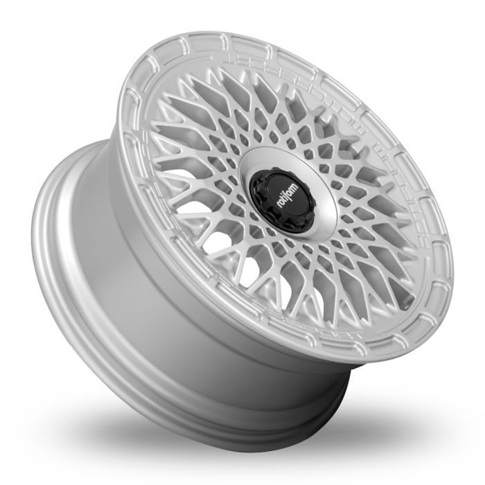 A detailed, luminous silver alloy wheel stands at an angle, showcasing its complex, interwoven spoke design with a central black cap featuring the text "rotiform." The foreground is shadowed white.