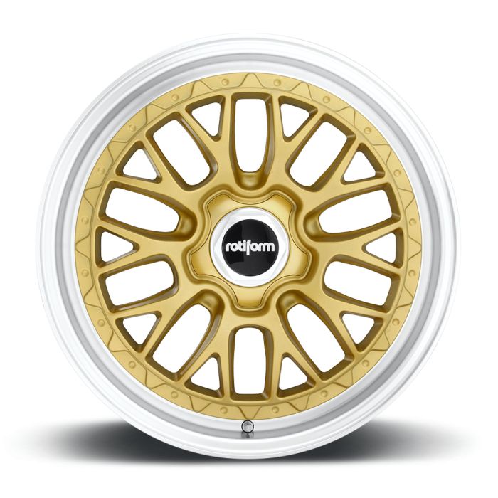 A gold alloy wheel with intricate, symmetrical spoke design and "rotiform" printed on the central black hub, set against a plain white background.