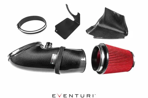 Carbon fiber car air intake kit, disassembled on a white background, including a large carbon fiber tube, a red air filter, a mounting bracket, a clamp, and a cover. Text: "Eventuri."
