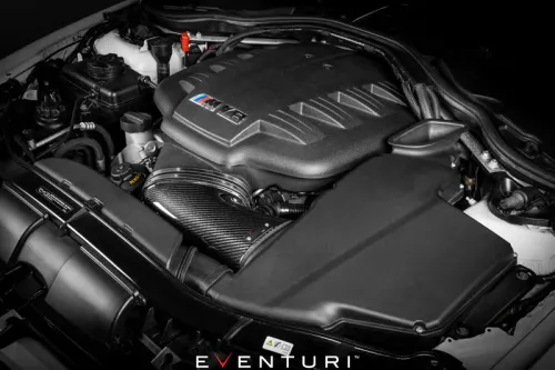An engine with a black plastic cover and "M5" logo is installed in a car's engine bay. It is branded "EVENTURI" at the bottom of the image.