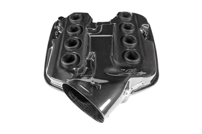 Carbon fiber automotive engine cover with six round openings, set on a white background.