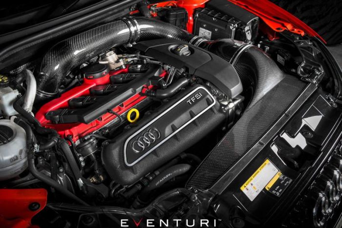 An Audi TFSI engine with a top cover displaying the Audi logo, situated in a vehicle engine bay with visible red and black components, Eventuri branding at the bottom center.