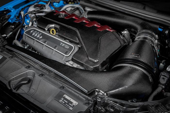 A carbon fiber-covered car engine with "TFSi" and Audi rings is mounted in a blue vehicle's engine compartment. The Venturi air intake system is prominent with sleek black tubing.