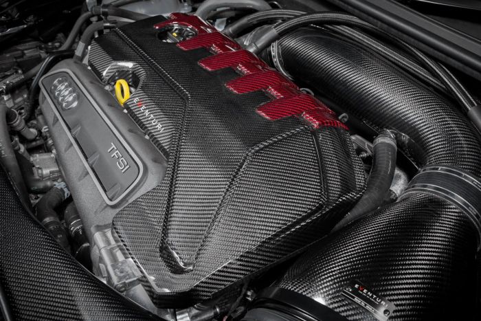 An Audi TFSI engine, featuring prominent carbon fiber components and red elements; situated in a detailed, high-performance car engine bay labeled "EVENTURI."