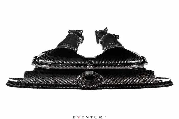 Carbon fiber dual intake system by Eventuri on a white background; featuring sleek design with two tubes and air filter housings. Text: “EVENTURI” on tubes and beneath the intake.