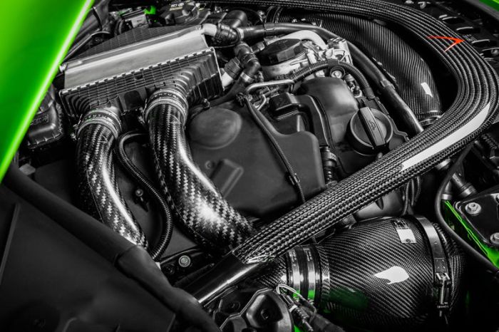 A car engine with intricate braided carbon fiber hoses and components. The context is under the hood of a vehicle highlighted with green accents on the edges.