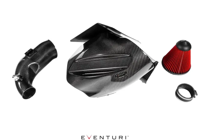 Carbon fiber car engine intake components lay on a white background. The central piece is a contoured box, with a cylindrical tube, a red conical air filter, and clamps around it. Text: EVENTURI.