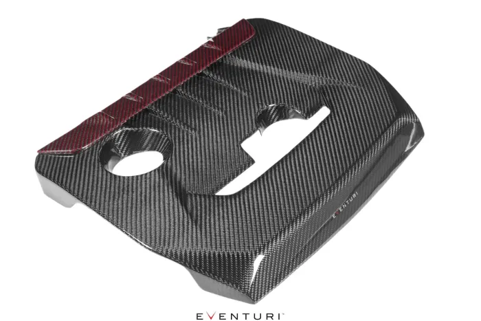 Carbon fiber engine cover with two circular openings at the top and a red-highlighted rear edge, resting on a white background. Text: "EVENTURI" at the bottom center.