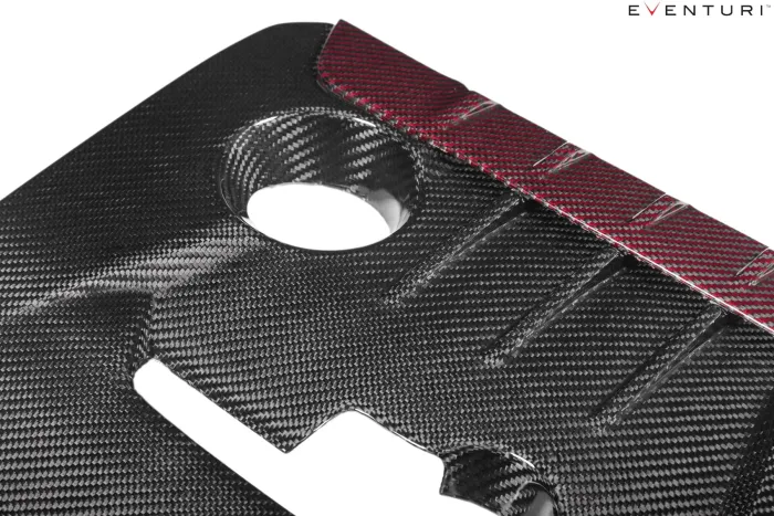 A carbon fiber engine cover features cutouts and textured patterns with a red stripe. "Eventuri" logo is in the top right corner.