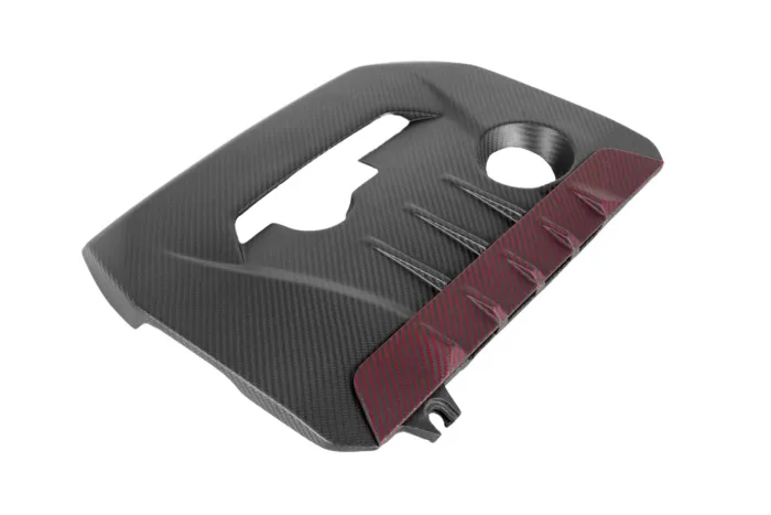 A carbon fiber engine cover with a rectangular cutout and circular hole, featuring a textured surface and red-striped section on its right side, isolated on a white background.