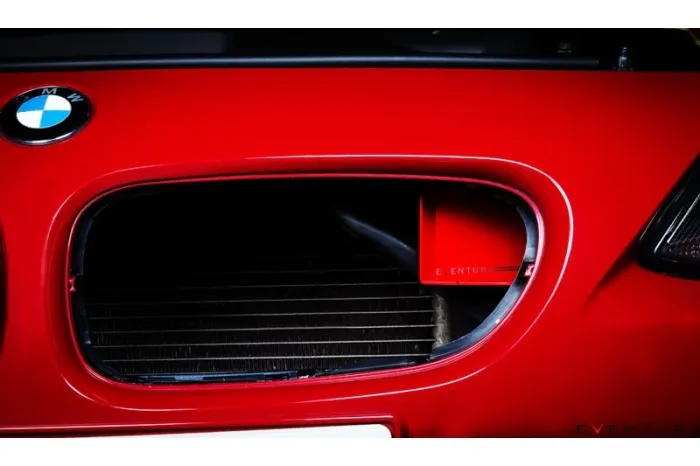 The front grille of a red BMW car features the BMW logo on the left and a visible air intake module labeled "EVENTURI."