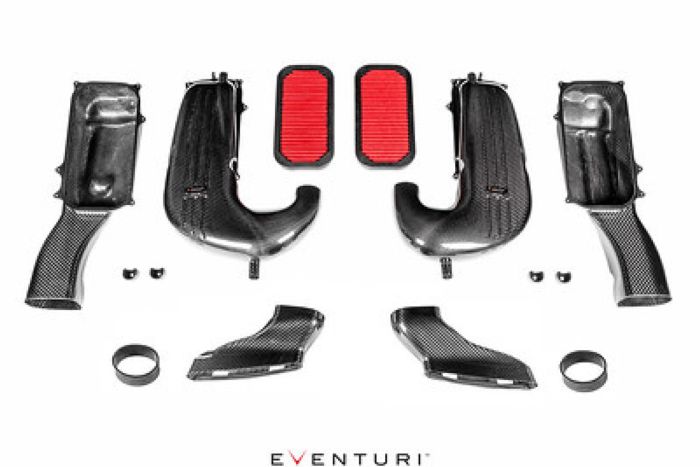 Carbon fiber automotive air intake kit, including curved ducts, cylindrical filters, couplers, and small components, laid out systematically on a white background. Text present: "EVENTURI."