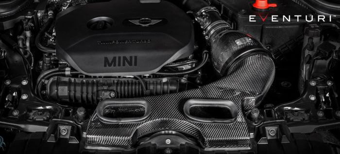 Engine compartment of a MINI car features a prominently displayed TwinPower Turbo engine cover and EVENTURI carbon fiber air intake system. The surroundings include various engine components and the Eventuri brand logo.